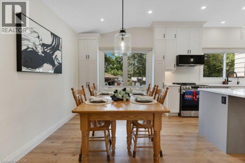 Wood-finish flooring, white cabinetry with dark hardware, recessed lighting, and a kitchen island with a light-toned countertop - 196 Abraham Street, Cambridge, ON 