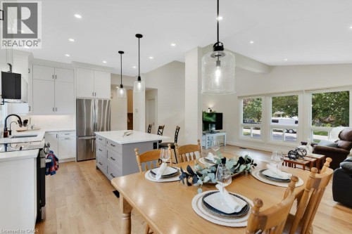 Open concept living space featuring wood-finish flooring, recessed lighting, white cabinetry, a kitchen island with stone countertop, and multiple large windows - 196 Abraham Street, Cambridge, ON 