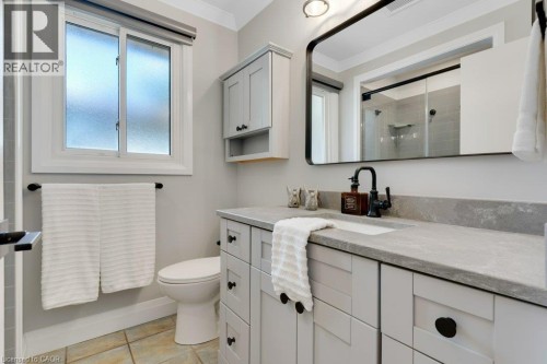 Modern bathroom featuring a single vanity with light grey cabinetry, a light-toned countertop, and a rectangular undermount sink - 196 Abraham Street, Cambridge, ON 
