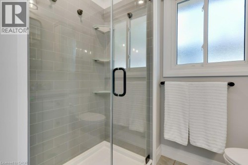 Glass-enclosed shower with subway tile surround, integrated shelving, and a frosted glass window - 196 Abraham Street, Cambridge, ON 