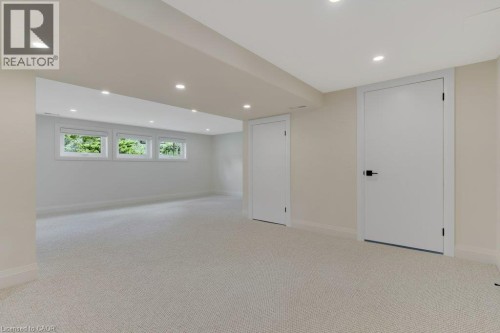 Spacious room featuring light-colored carpeting, three transom windows, recessed lighting, and two white doors - 196 Abraham Street, Cambridge, ON 