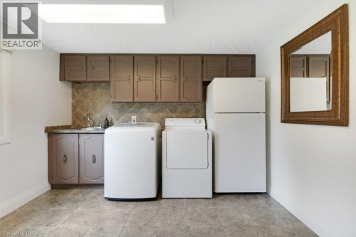 Spacious laundry room featuring tile flooring, built-in cabinetry, an integrated sink, and a tiled backsplash - 196 Abraham Street, Cambridge, ON 