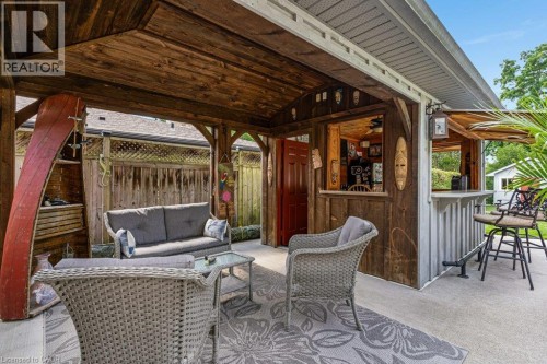 Covered patio with a wood-finish ceiling, featuring a built-in bar, wood-paneled walls, and a concrete floor - 196 Abraham Street, Cambridge, ON 
