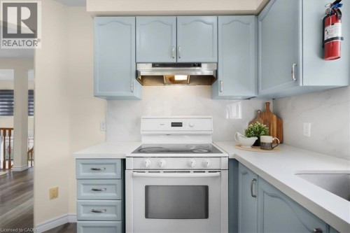 Light blue cabinetry with silver-tone hardware, white countertops, and a white tile backsplash - 150 Bankside Drive, Kitchener, ON 
