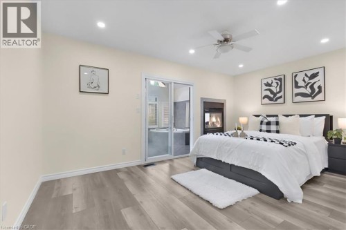 Wood-finish flooring, recessed lighting, ceiling fan, built-in fireplace, and sliding glass door - 150 Bankside Drive, Kitchener, ON 