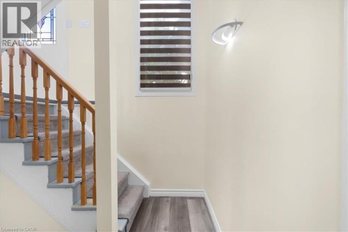 Staircase with wood newel posts and handrail, carpeted treads, and stained glass window accent - 150 Bankside Drive, Kitchener, ON 