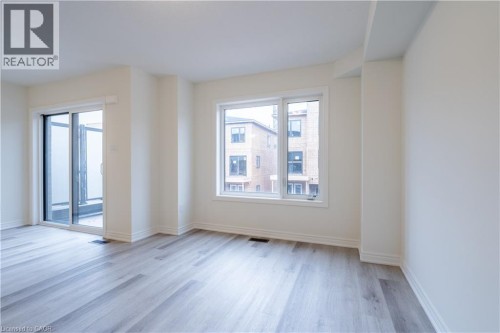 Wood-finish flooring, white walls, and a large window with white trim - 23 Dryden Lane, Hamilton, ON 