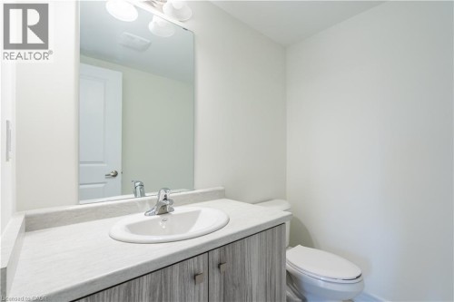 Vanity with a surface-mounted sink, chrome faucet, wood-finish cabinetry, and an overhead light fixture - 23 Dryden Lane, Hamilton, ON 