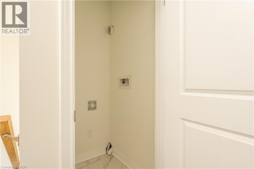 Dedicated laundry area featuring a floor drain, electrical outlet, and water hookups - 23 Dryden Lane, Hamilton, ON 