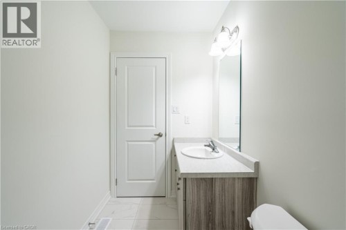 Modern bathroom featuring a wood-finish vanity with an integrated rectangular sink, chrome faucet, and ample counter space - 23 Dryden Lane, Hamilton, ON 