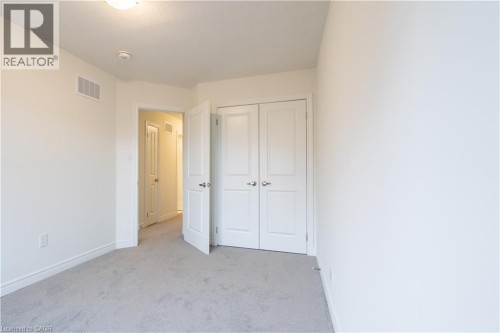 Soft neutral wall color, carpet flooring, and a flush mount ceiling light - 23 Dryden Lane, Hamilton, ON 