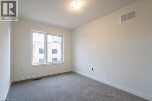 Bright interior space featuring a double window, overhead flush-mount lighting, light gray carpeting, and white wall finishes - 23 Dryden Lane, Hamilton, ON 