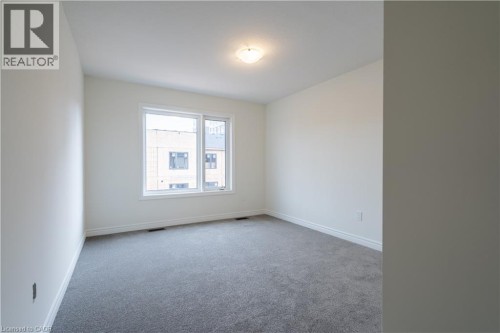 White walls with window trim, grey carpet flooring, and a ceiling-mounted light fixture - 23 Dryden Lane, Hamilton, ON 