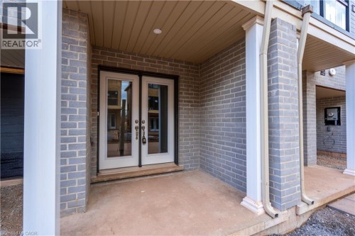 Gray brick exterior with white double-pane French doors, concrete entryway, and architectural columns - 23 Dryden Lane, Hamilton, ON 