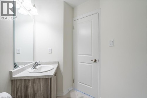 Vanity with wood-finish cabinetry, integrated sink, and light-toned countertop - 23 Dryden Lane, Hamilton, ON 