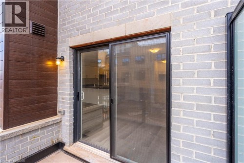 Sliding glass doors, exterior wall sconce, brick exterior, wood-finish siding, and stone window sill - 23 Dryden Lane, Hamilton, ON 