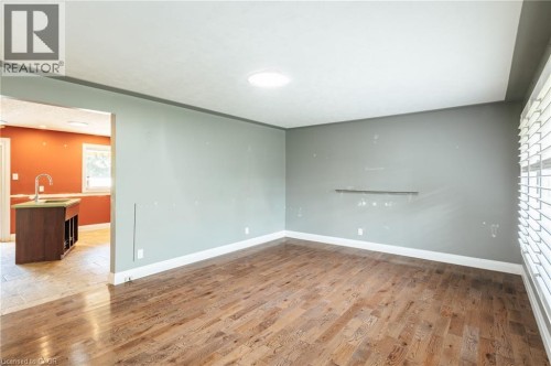 Hardwood flooring, natural light via window with blinds, recessed lighting, and an adjacent kitchen with tile flooring and a built-in sink - 229 Winfield Avenue, Waterloo, ON 