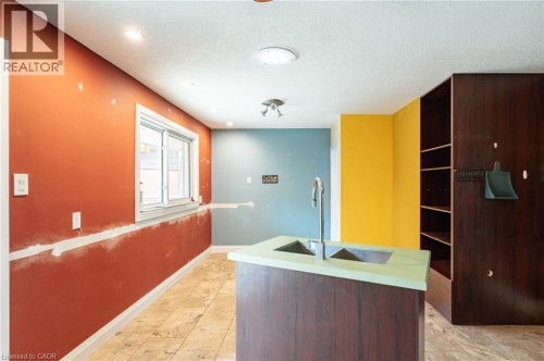 Central island with double basin sink and gooseneck faucet, built-in shelving, recessed lighting, and tile flooring - 229 Winfield Avenue, Waterloo, ON 