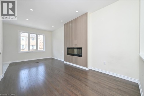 Hardwood flooring throughout, recessed ceiling lighting, a contemporary fireplace feature wall, an inset linear electric fireplace, and multi-pane windows - 64 Maple Cider Street, Caledon, ON 