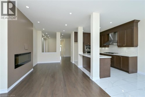 Built-in linear fireplace with slatted wall accent, recessed lighting, wood-finish flooring, dark wood cabinetry, and white tile flooring - 64 Maple Cider Street, Caledon, ON 