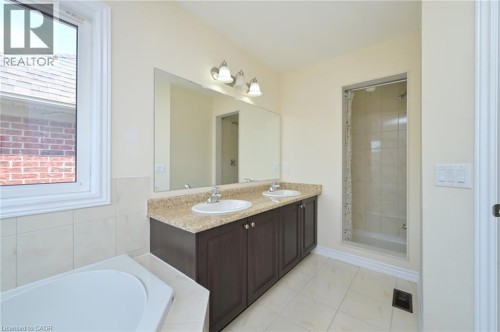Double vanity with integrated sinks, granite-style countertop, and dark wood cabinetry - 64 Maple Cider Street, Caledon, ON 