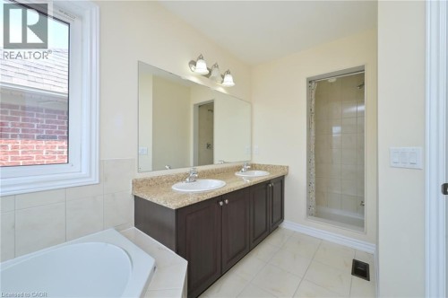 Dual vanity with granite-style countertop, integrated sinks, and dark wood-finish cabinetry - 64 Maple Cider Street, Caledon, ON 