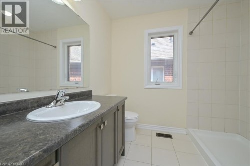 Bathroom featuring a vanity with an integrated oval sink, chrome faucet, and expansive wall mirror - 64 Maple Cider Street, Caledon, ON 