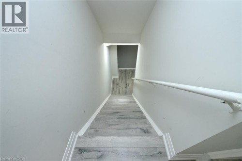Stairway featuring wood-finish flooring, light wall tones, and a wall-mounted handrail - 64 Maple Cider Street, Caledon, ON 