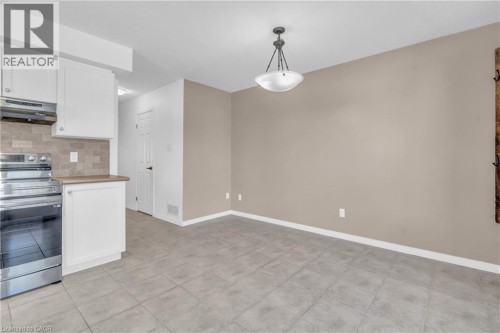 Stainless steel range and hood, white shaker-style cabinetry, tile backsplash, laminate countertops, and tile flooring - 50 Howe Drive Unit# 19B, Kitchener, ON 