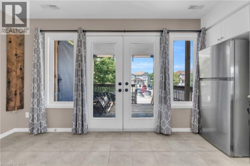 Dual French doors flanked by windows, tile flooring, and integrated stainless steel refrigerator - 50 Howe Drive Unit# 19B, Kitchener, ON 