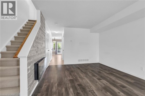 Rich wood-finish flooring complements the modern wall-mounted fireplace - 50 Howe Drive Unit# 19B, Kitchener, ON 