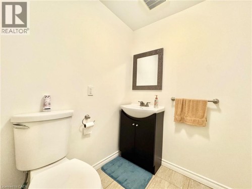 Tile flooring, a dark wood-finish vanity with an integrated sink, and a wall-mounted mirror - 1335 Countrystone Drive, Kitchener, ON 