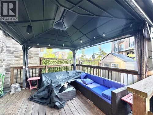 Expansive outdoor deck featuring a dark-toned gazebo with string lighting, wood-finish decking, and robust wood railings - 1335 Countrystone Drive, Kitchener, ON 
