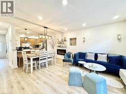 Open-concept living area featuring wood-finish flooring, recessed lighting, and wall sconces - 