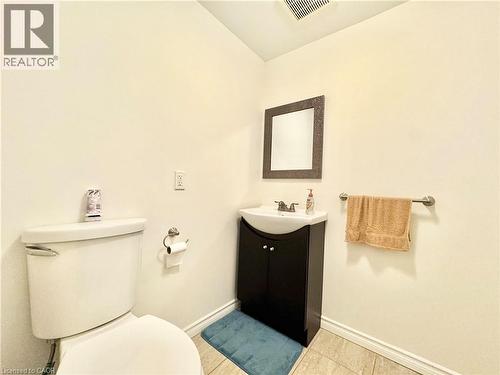 Tile flooring, a dark wood-finish vanity with an integrated sink, and a wall-mounted mirror - 1335 Countrystone Drive, Kitchener, ON 