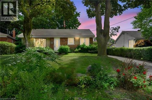 Brick exterior, expansive front lawn, mature trees, established landscaping, and a paved driveway - 1046 Shepherds Drive, Burlington, ON 