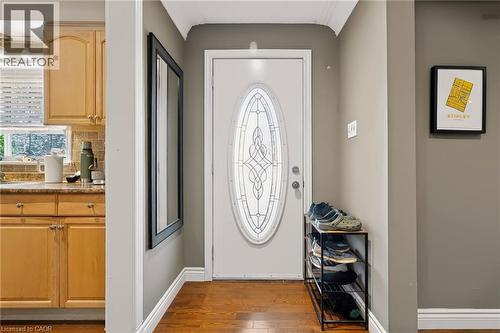 Entry door with decorative oval glass insert, wood-finish flooring, and crown molding - 1046 Shepherds Drive, Burlington, ON 