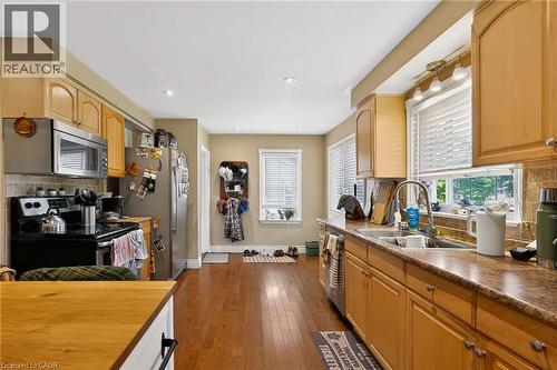 Wood-finish flooring, recessed lighting, double basin sink, light wood cabinetry, and stainless steel appliances - 1046 Shepherds Drive, Burlington, ON 
