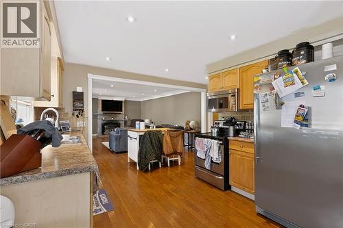 Kitchen featuring stainless steel appliances, wood-finish cabinetry, granite-style countertops, and wood-finish flooring - 1046 Shepherds Drive, Burlington, ON 