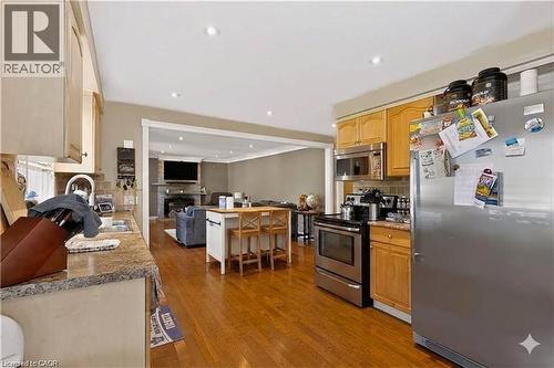 Kitchen with wood-finish flooring, stainless steel appliances, recessed lighting, and a kitchen island with seating - 1046 Shepherds Drive, Burlington, ON 