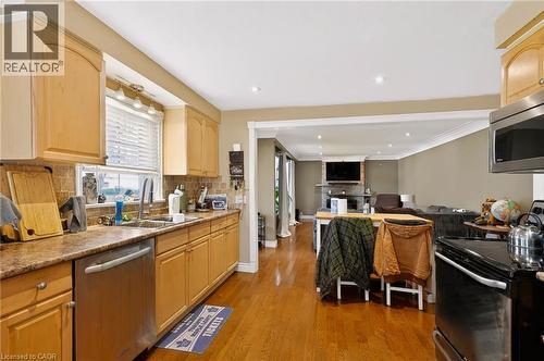 Kitchen featuring wood-finish cabinetry, stainless steel dishwasher, and a stone-finish countertop - 1046 Shepherds Drive, Burlington, ON 