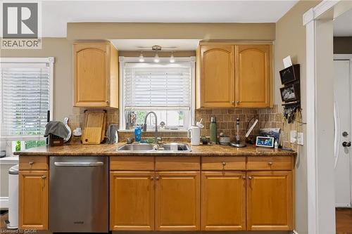 Wood-finish cabinetry, stainless steel dishwasher, tile backsplash, dual basin stainless steel sink, and light-tone countertops - 1046 Shepherds Drive, Burlington, ON 