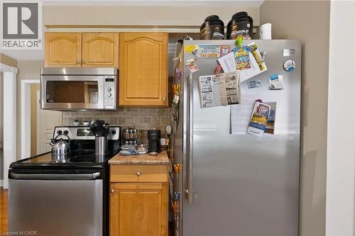 Light wood-finish cabinetry, stainless steel microwave, black electric range with stainless steel accent, and stone-finish backsplash - 1046 Shepherds Drive, Burlington, ON 