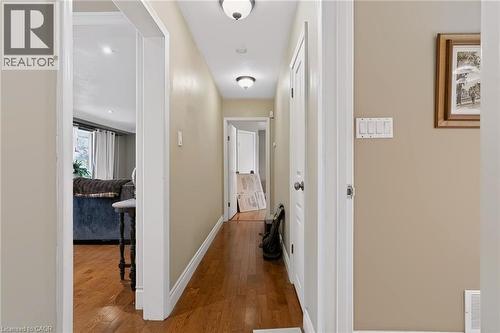 Hardwood flooring extending through a hallway with overhead lighting and white trim - 1046 Shepherds Drive, Burlington, ON 