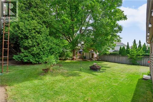 Expansive backyard featuring a manicured lawn, mature trees, a wooden privacy fence, and two storage sheds - 1046 Shepherds Drive, Burlington, ON 