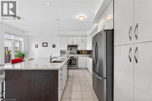 Kitchen with stainless steel appliances, a kitchen breakfast bar, light tile patterned flooring, and an island with sink - 97 Sirente Drive, Hamilton, ON 