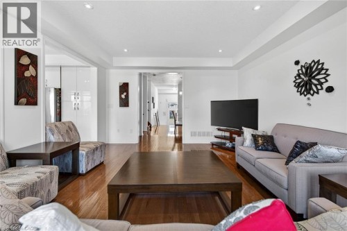 Living room with wood finished floors, a tray ceiling, and recessed lighting - 97 Sirente Drive, Hamilton, ON 