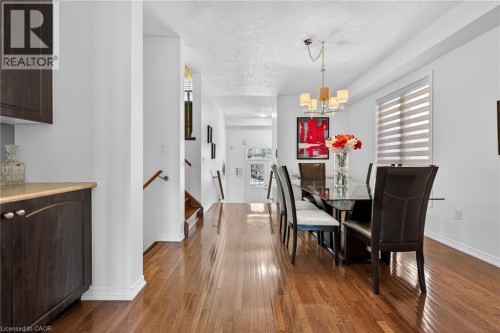 Dining area featuring a textured ceiling, dark wood-style floors, plenty of natural light, and suspended lighting - 97 Sirente Drive, Hamilton, ON 