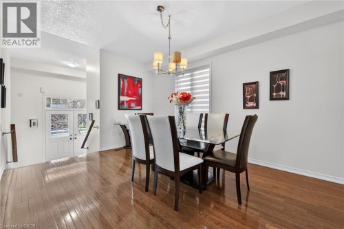 Dining room with dark wood-style floors, hanging lights, and a textured ceiling - 97 Sirente Drive, Hamilton, ON 