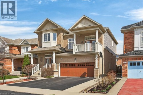 Craftsman inspired home featuring an attached garage, asphalt driveway, a balcony, and brick siding - 97 Sirente Drive, Hamilton, ON 